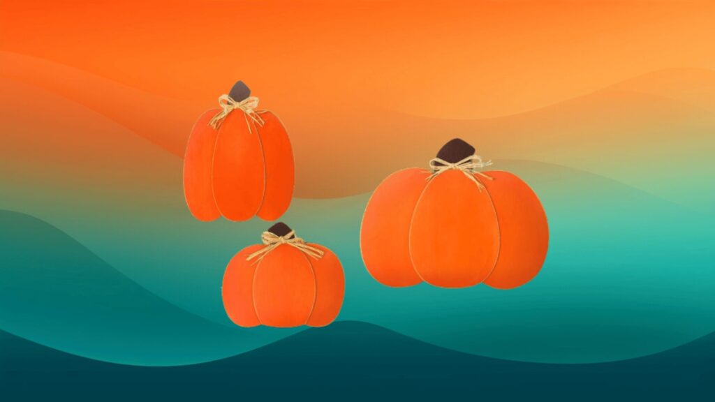 three orange wooden pumpkins in front of an orange and teal background
