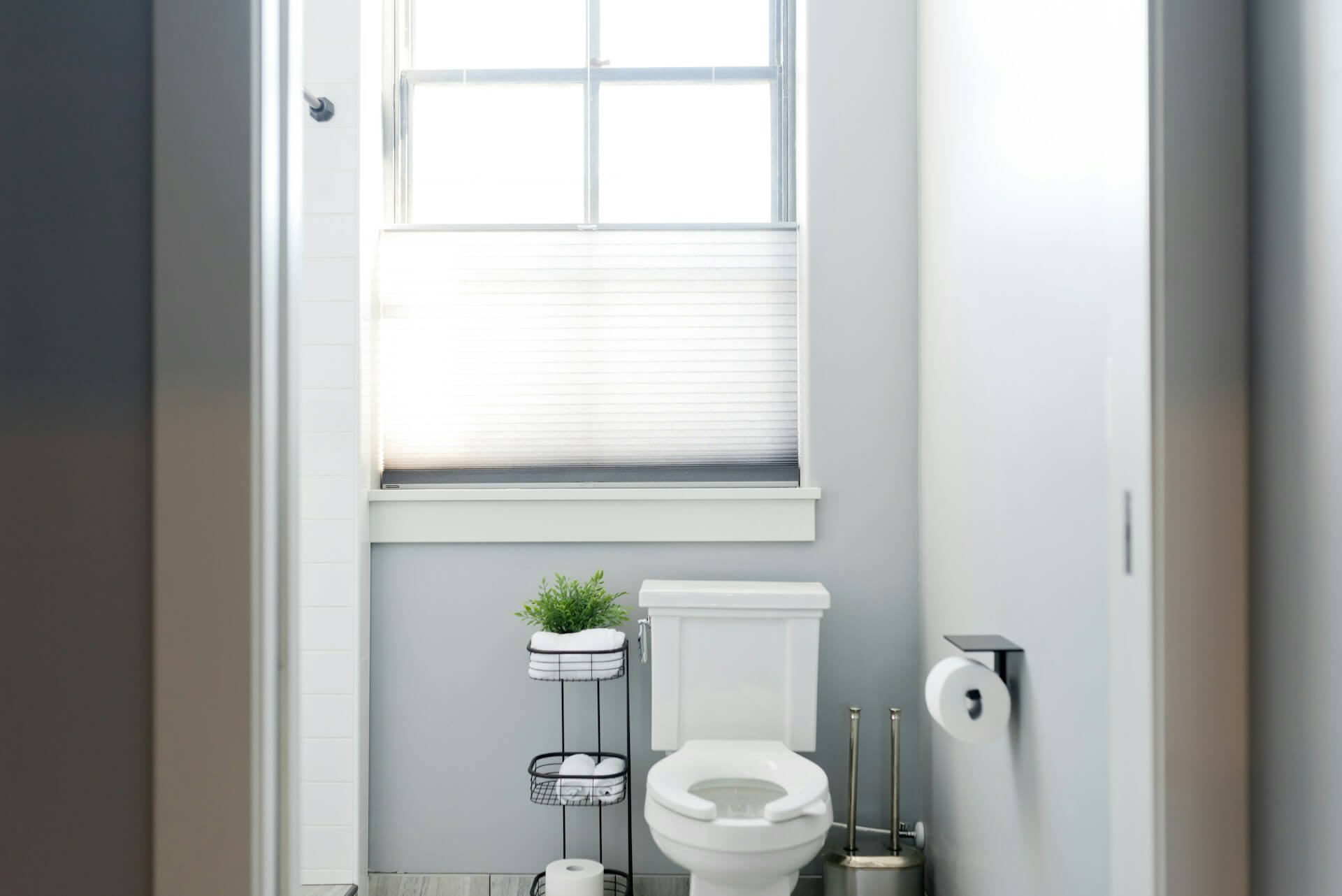 White toilet installed beside a window in a bright bathroom, an example of the standard fixture a macerating toilet can replace