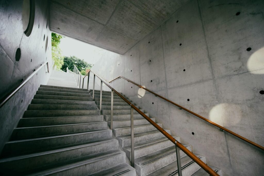 Empty gray concrete staircase with a metal handrail