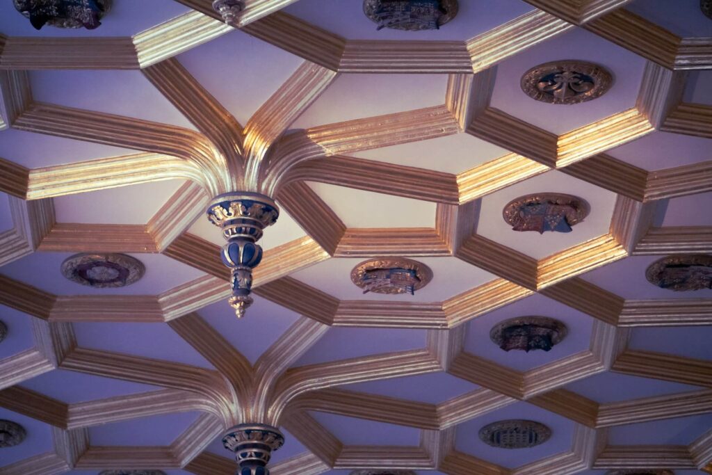 Ornate historic ceiling at Hampton Court Palace with a clock and hanging chandelier