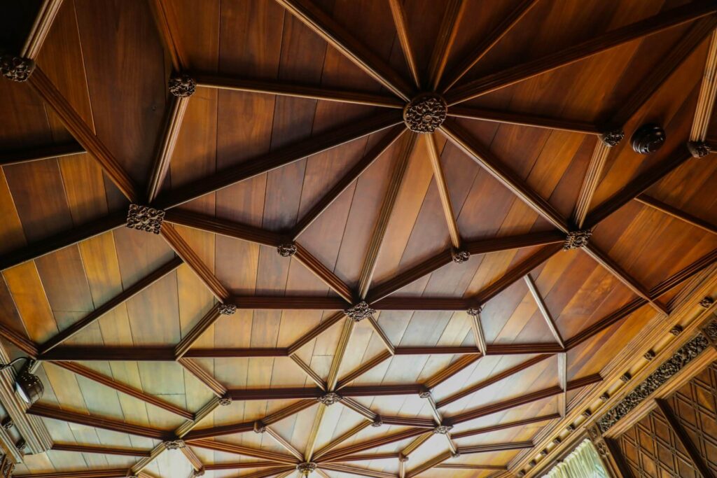 Brown wooden ceiling with a hanging light fixture in an arched building exterior