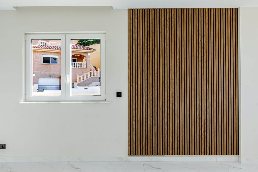 Wood wall paneling with natural grain texture beside a window in a modern interior