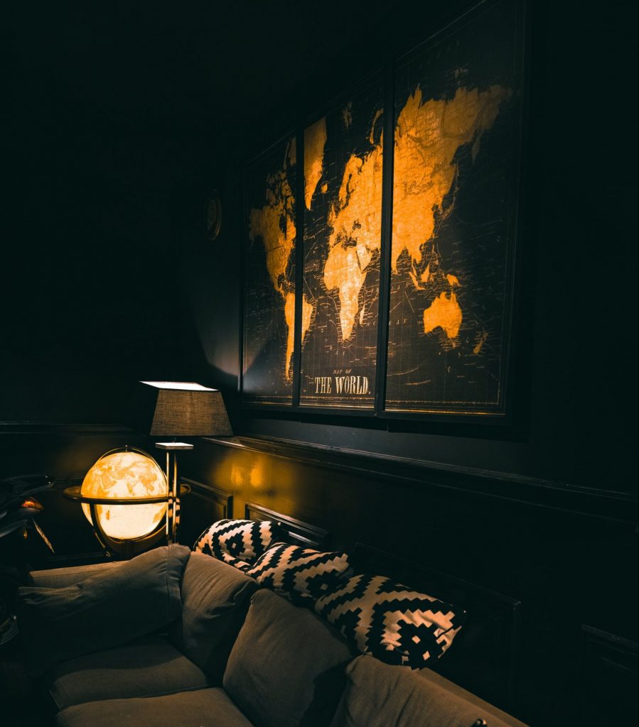 A dark, black painted living room with a gold globe and world map