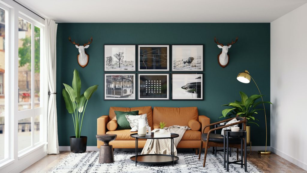 A living room with black and white paintings hung on a green accent wall
