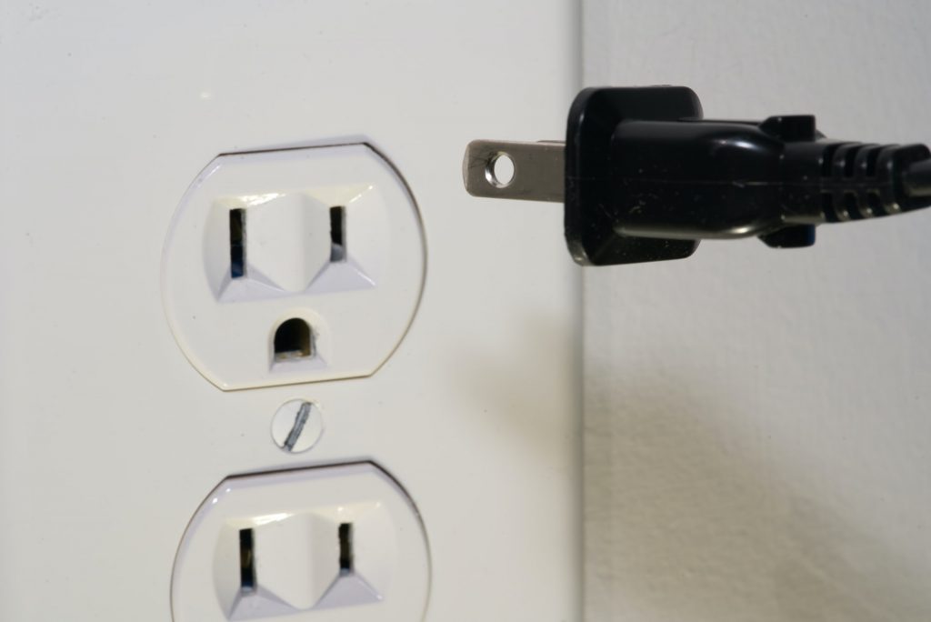 A black plug going into a white outlet