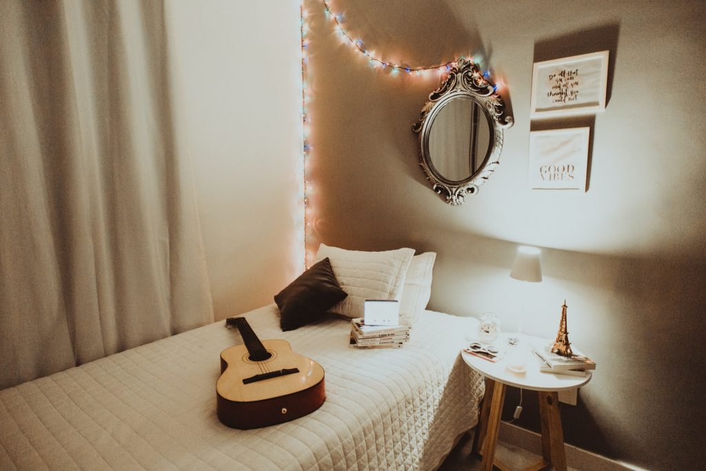 Small bedroom with colorful string lights and a small white lamp