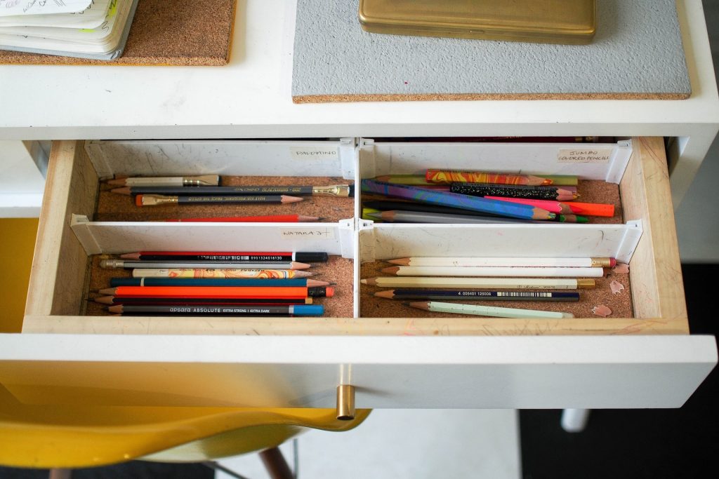 A white drawer with white drawer dividers to separate pencils