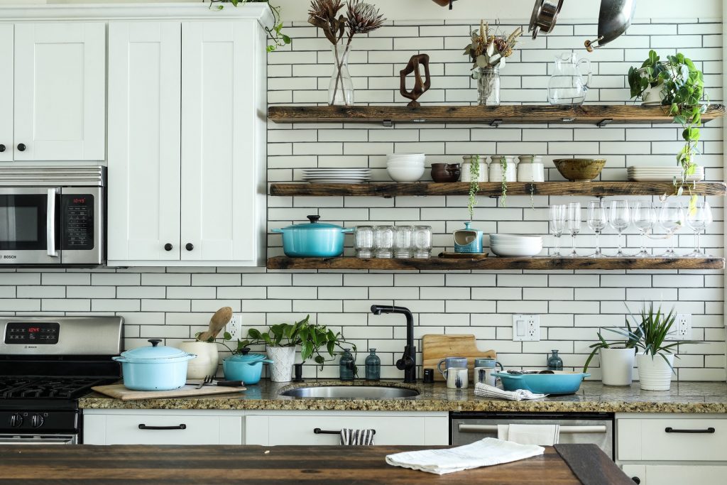 Cluttered kitchen with filled wooden shelfs and crowded counters