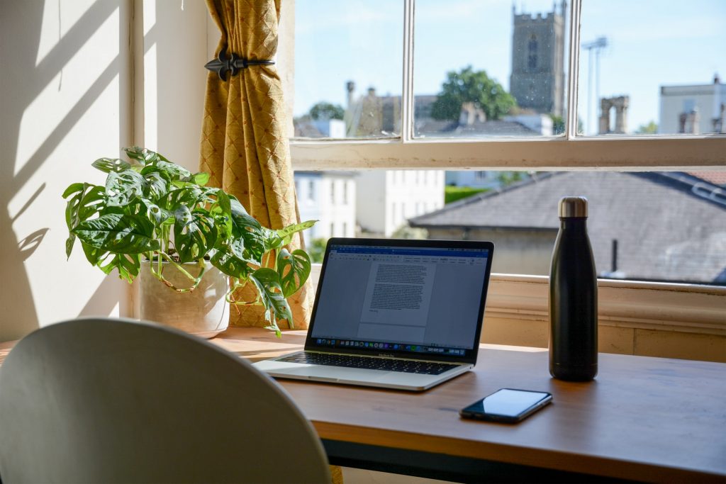 A laptop on a desk by an open window to impact your home office productivity