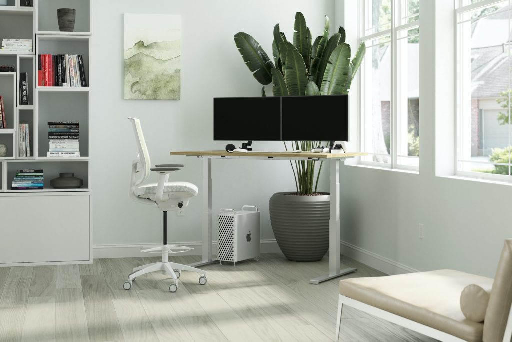 White standing desk and white ergonomic office chair near a window