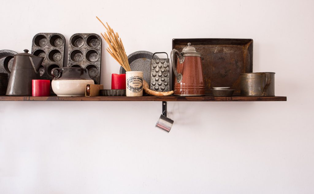 A variety of cooking utensils and tools on a wooden shelf to be orgaanized in kitchen cabinets