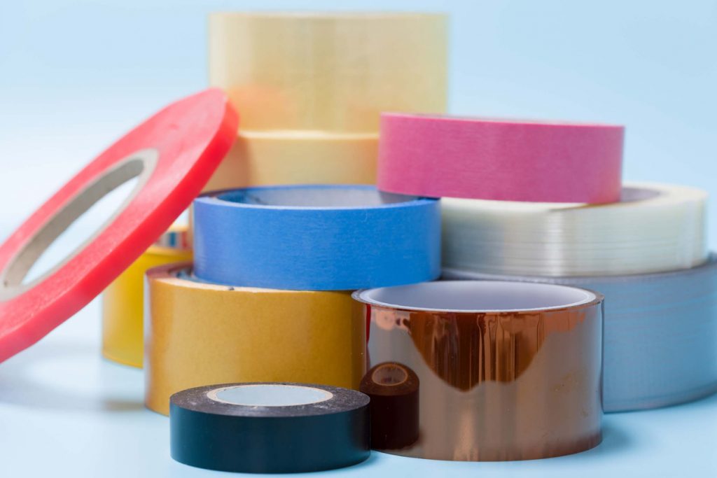 Multiple rolls of colorful, multisized duct tape against a blue background