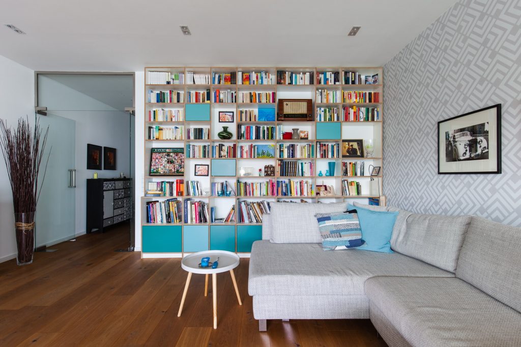 A living room with a wall of built-in shelving with blue accents
