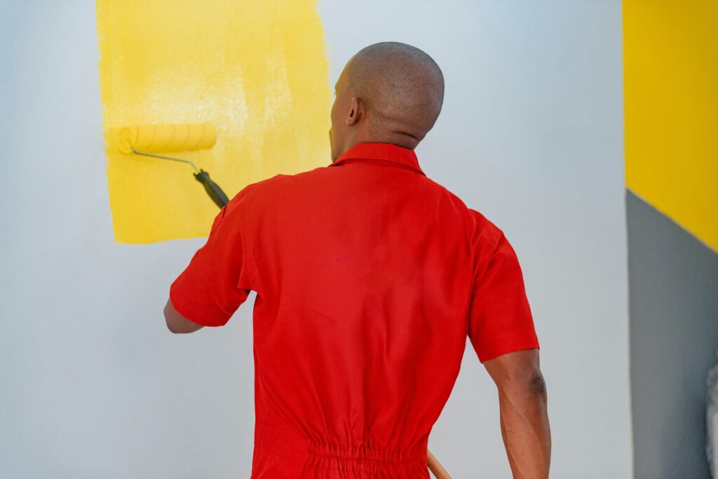 guy putting a fresh coat of paint in his room to improve home value