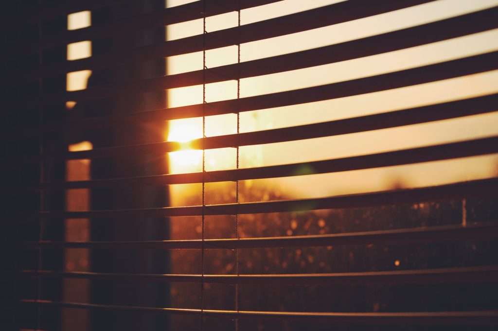 A sunset peeking through open vertical blinds