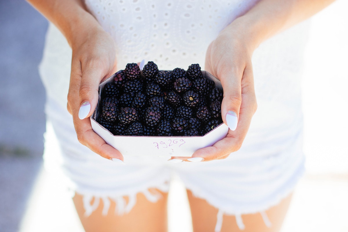 a woman wearing white holding blackberries