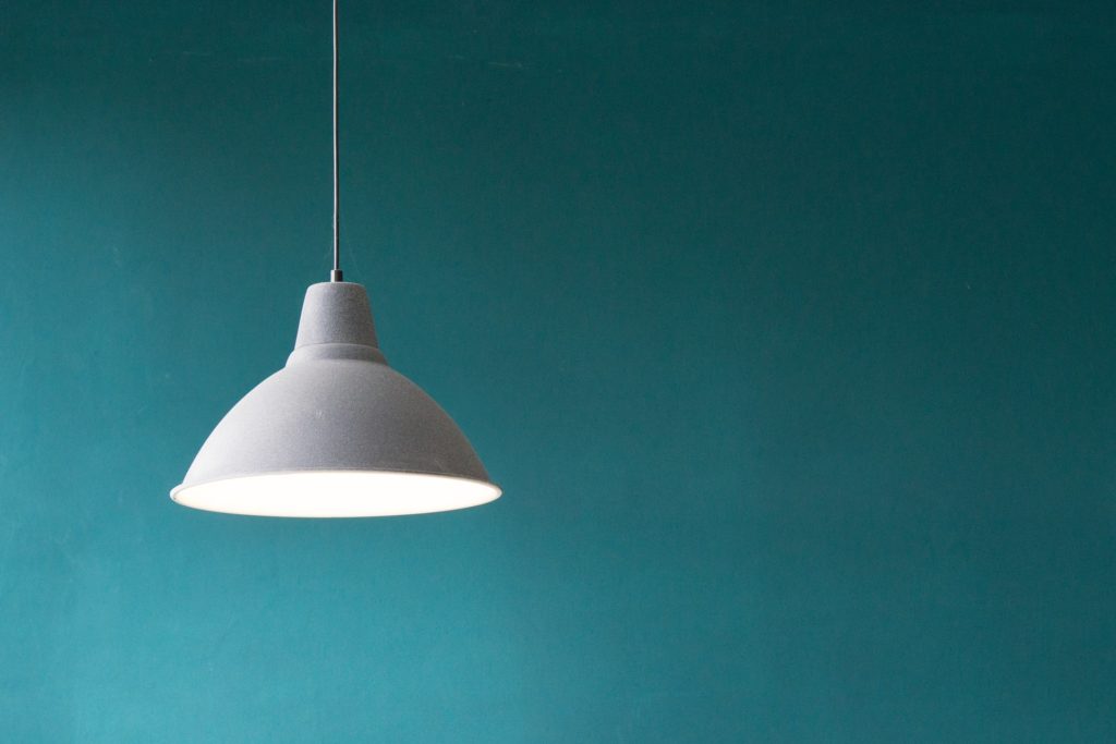 a white hanging light and a blue wall