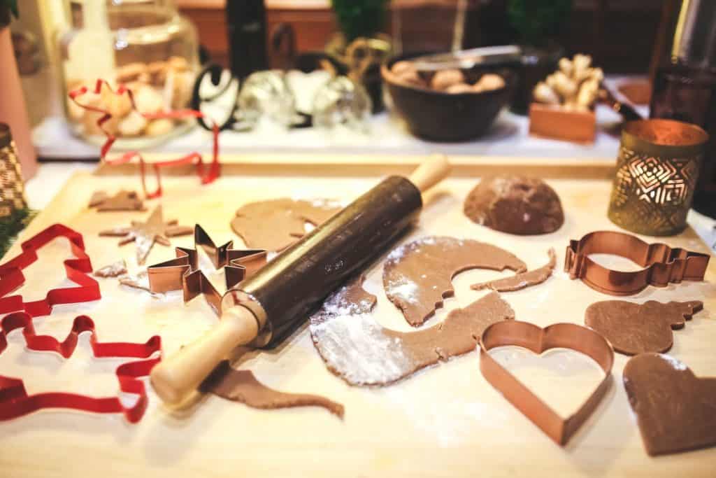 gingerbread dough cut out into shapes near a rolling pin