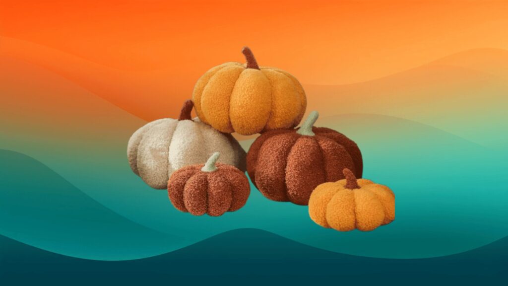 five plush pumpkin pillows in orange, red, and cream in front of an orange and teal background