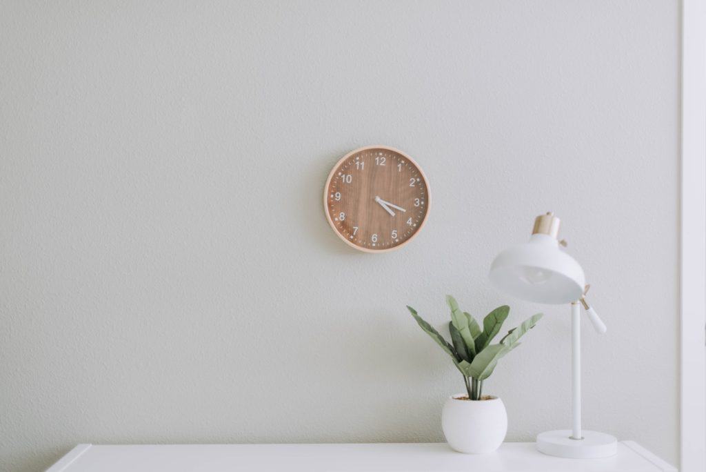 a minimalist setting with white walls and a clock with flowers