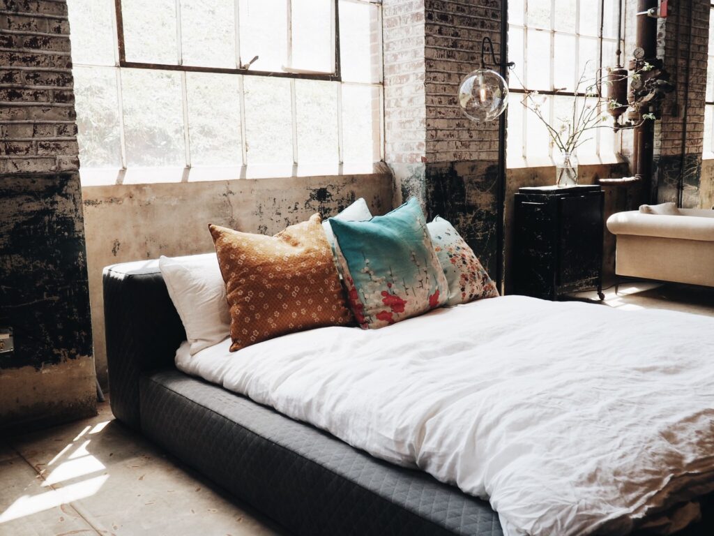 an industrial accented bedroom with large bright windows and dangling lights