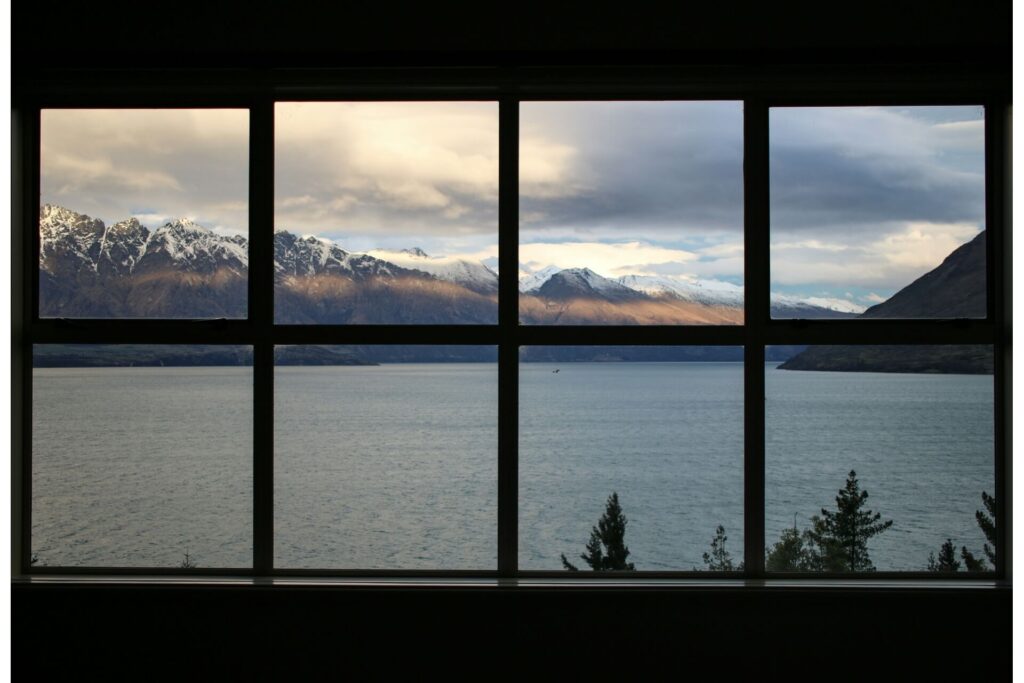 An energy-efficient window framing a lake and mountainscapes.