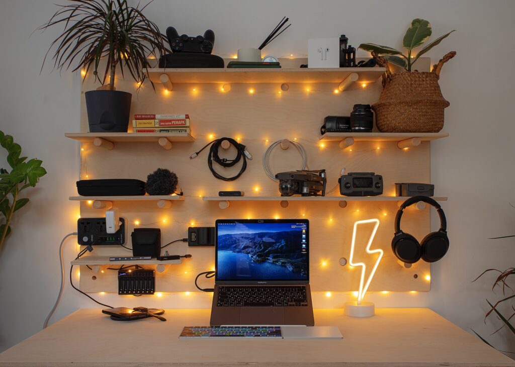 a string-lit computer desk with oractical objects on floating wooden shelves and pegs