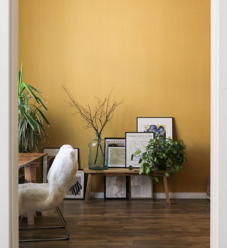 a room with light yellow walls and paintings on the floor