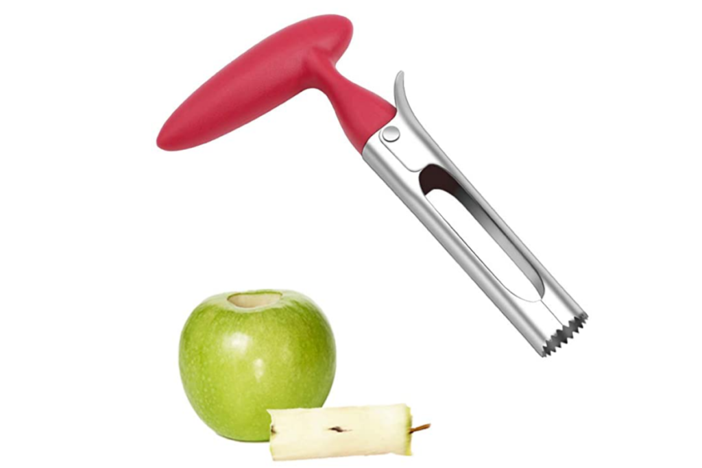 An apple corer with a red handle next to a green apple