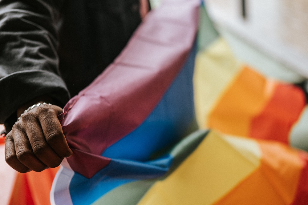 a person holding a LGBTQ+ rainbow flag
