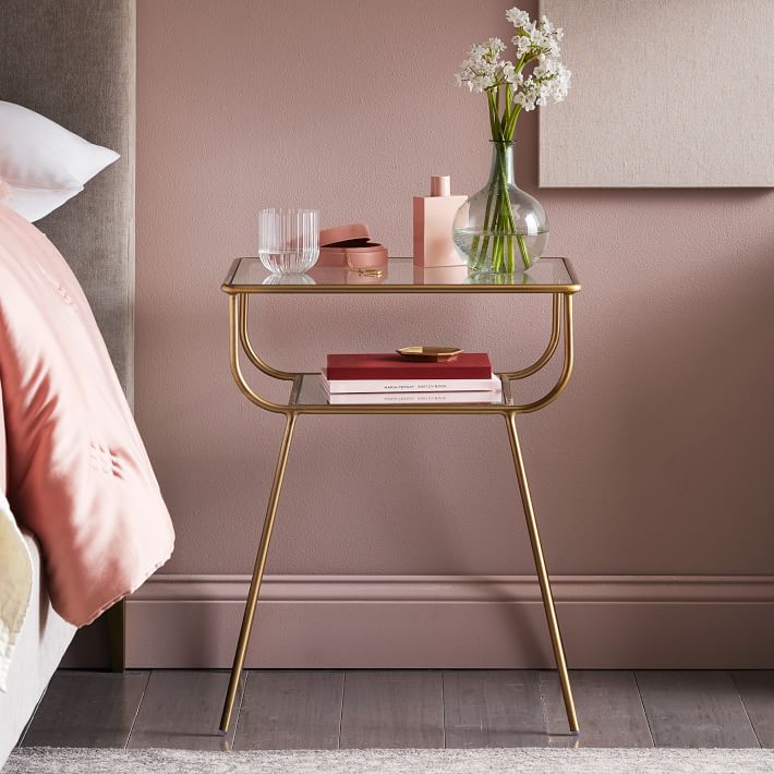 a golden metal side table in a pink room