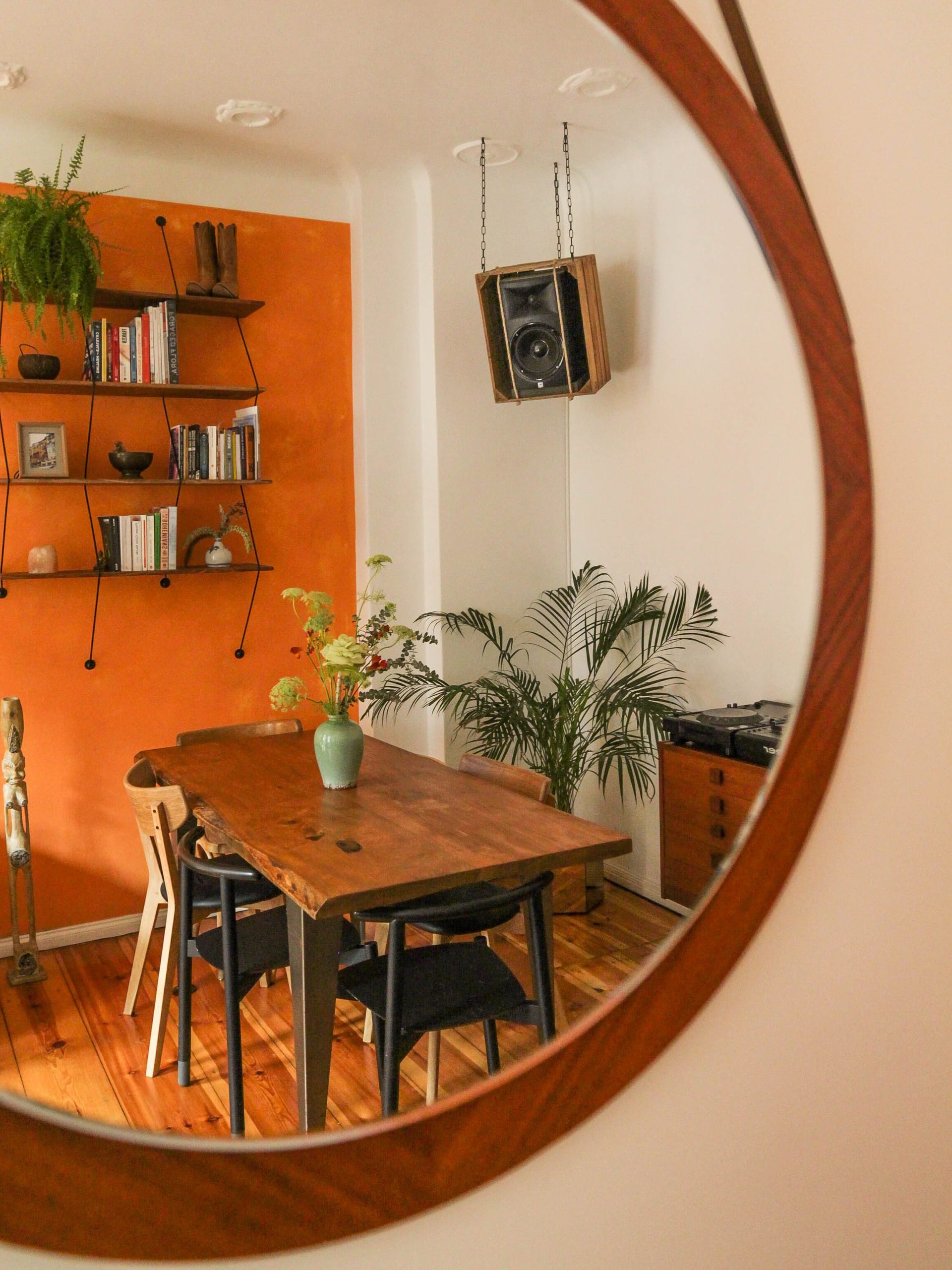 A dining room being shown through a mirror with an orange accent wall