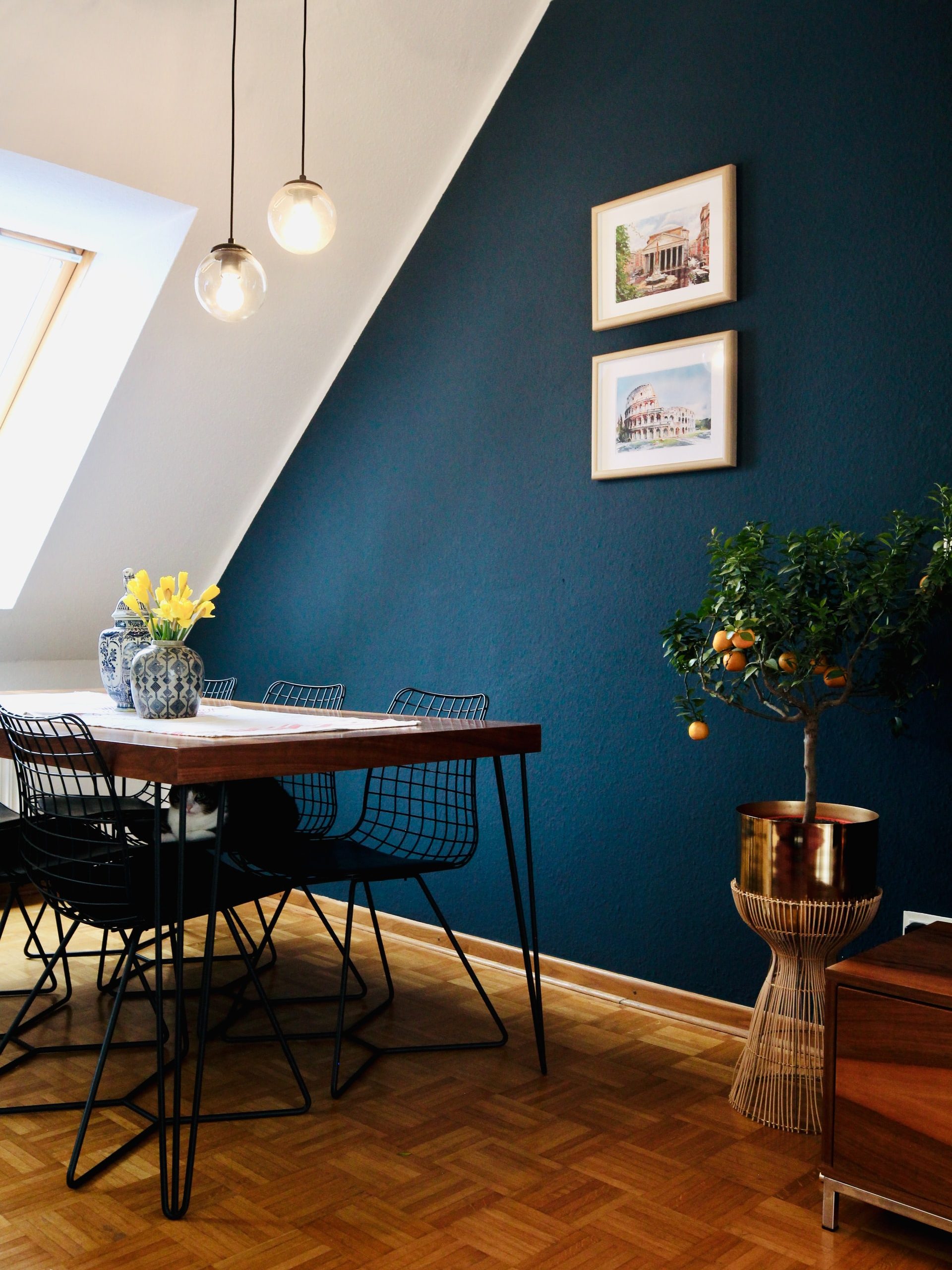 A dining room with a white slanted wall and a navy blue accent wall