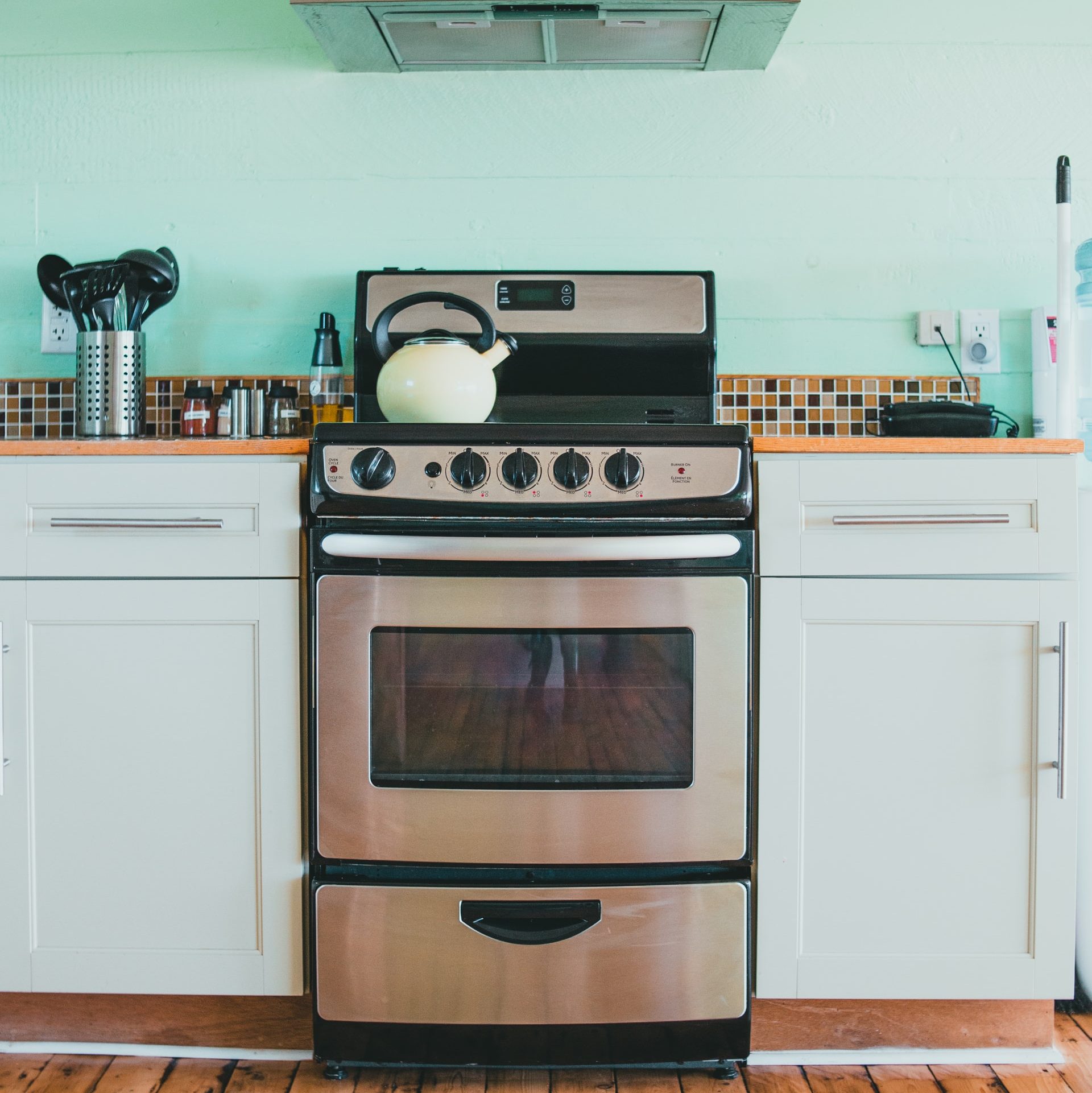 A silver and black stove in a green kitchen