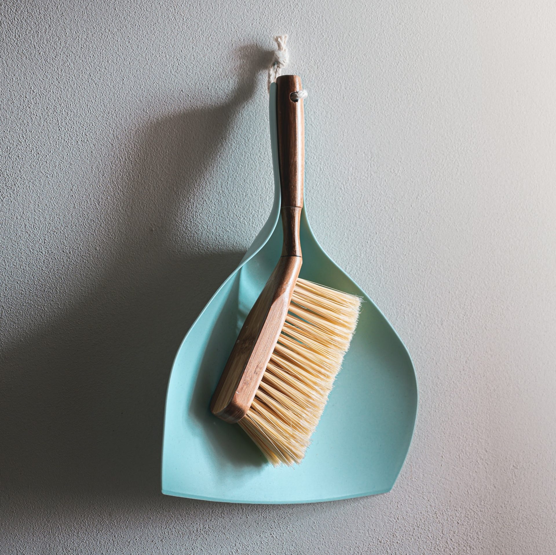 Handheld dust broom with a teal dustpan