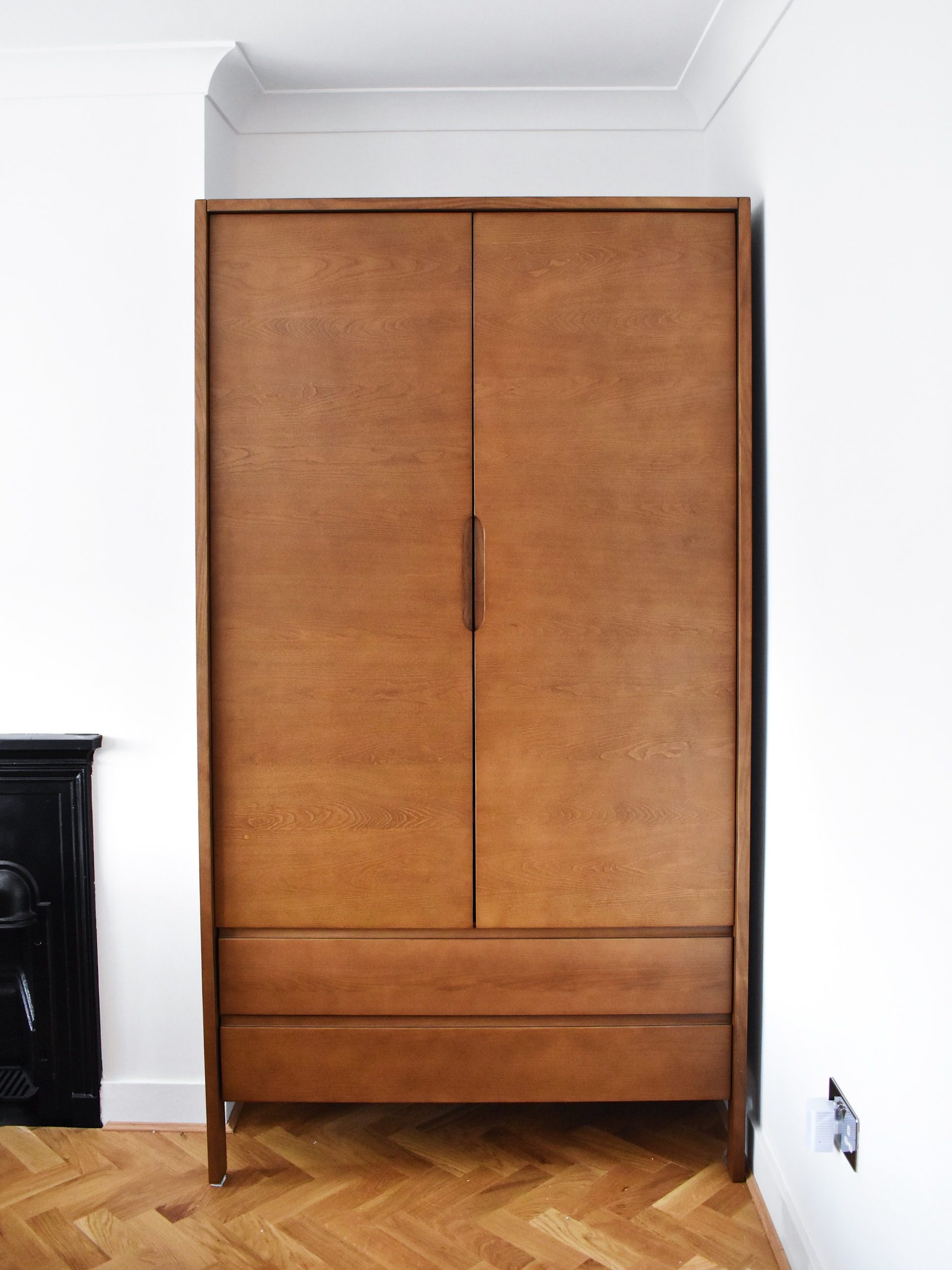 A brown wardrobe in a corner of a white room