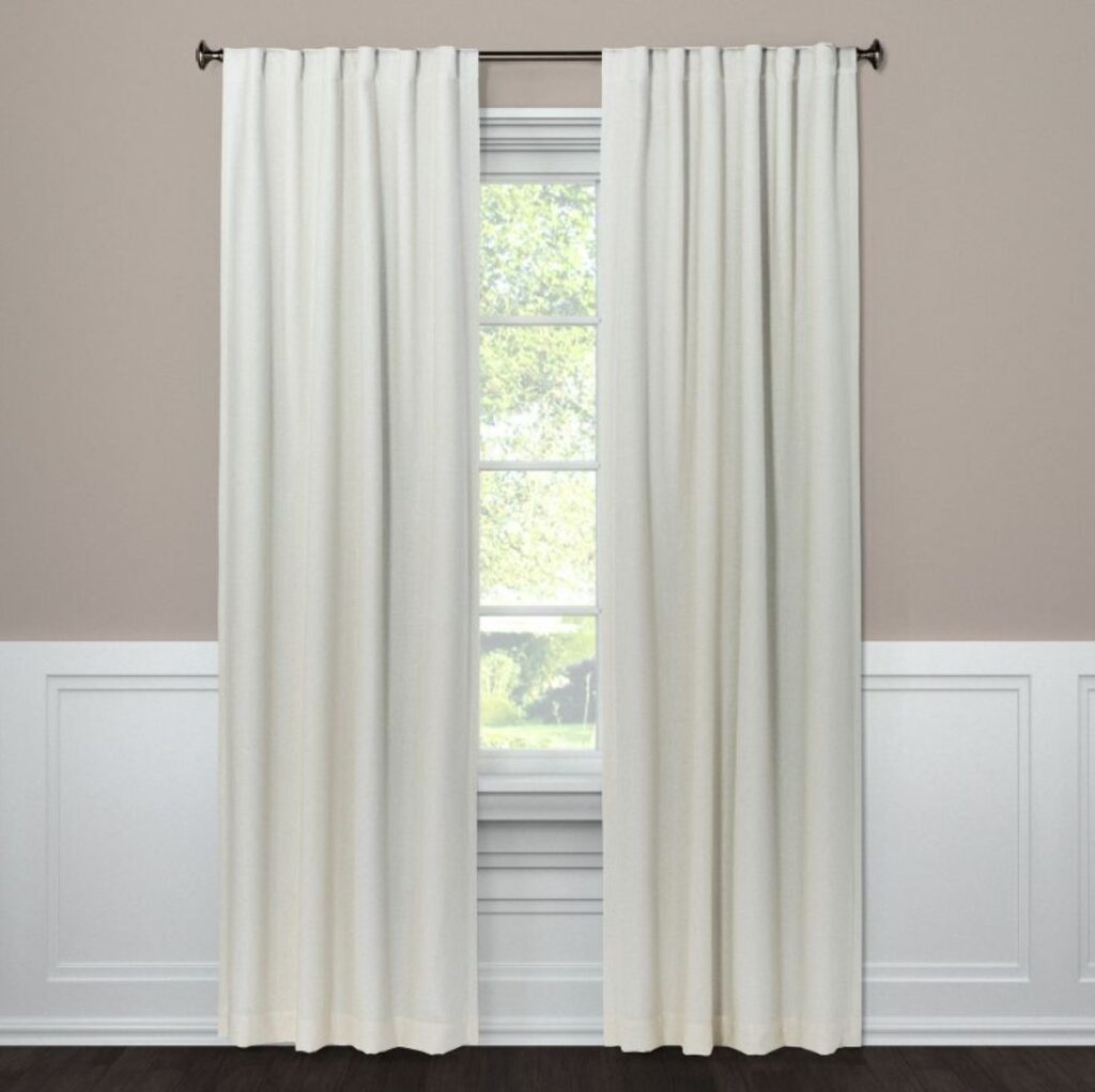 white panel curtains hanging against a beige wall with white moulding