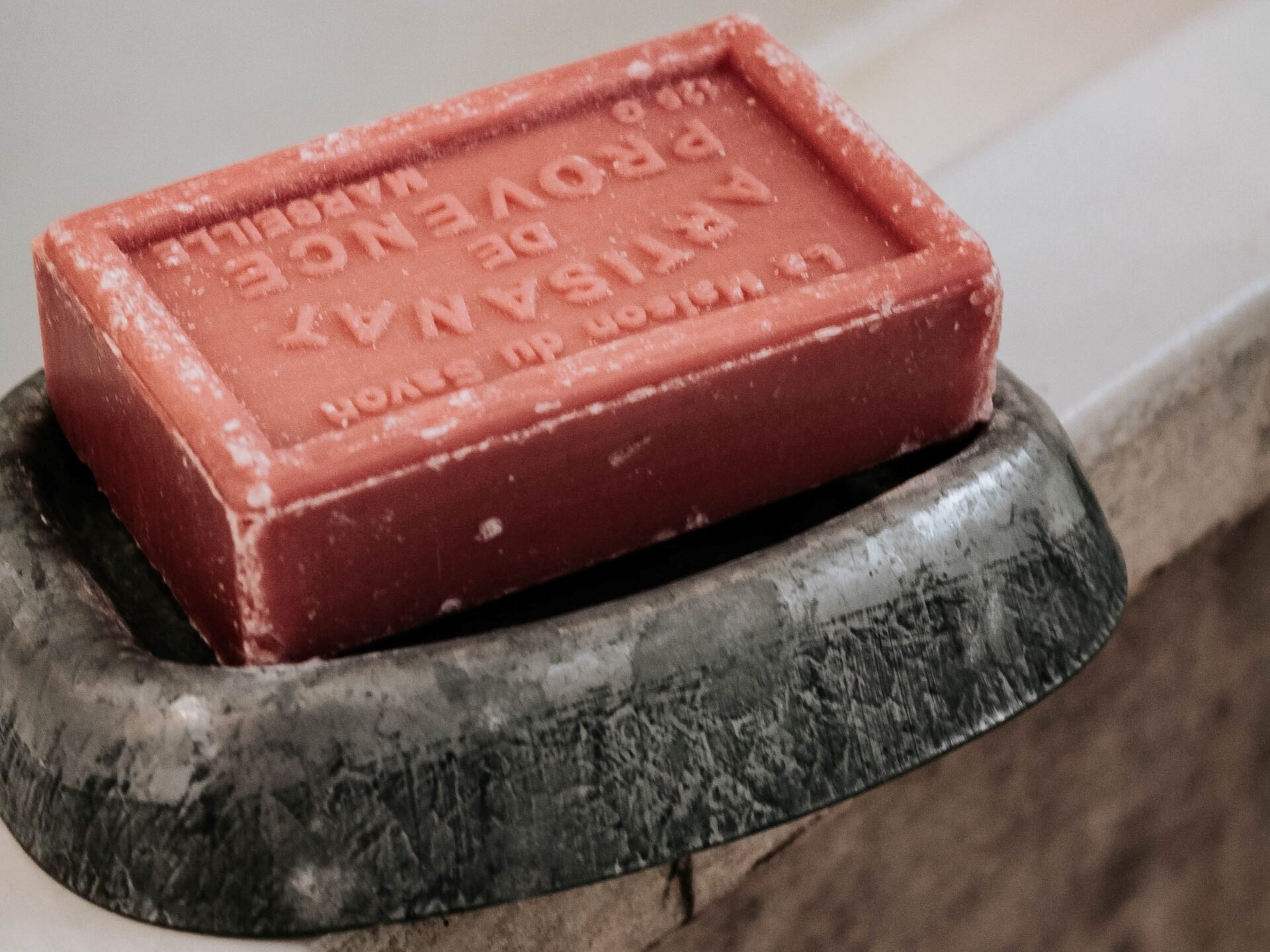 a red bar of soap in a soap dish on the edge of the tub for your minimalist shower caddy