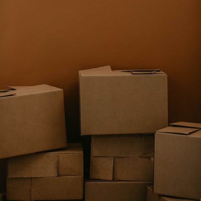 a stack of multiple cardboard boxes against a brown wall