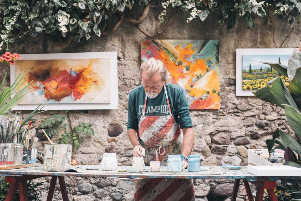 an artist in an apron working outside on art