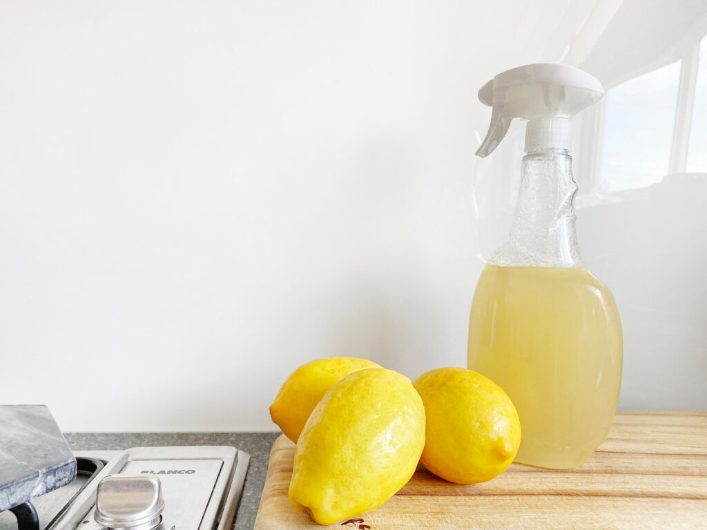 three lemons near a spray bottle of lemon juice