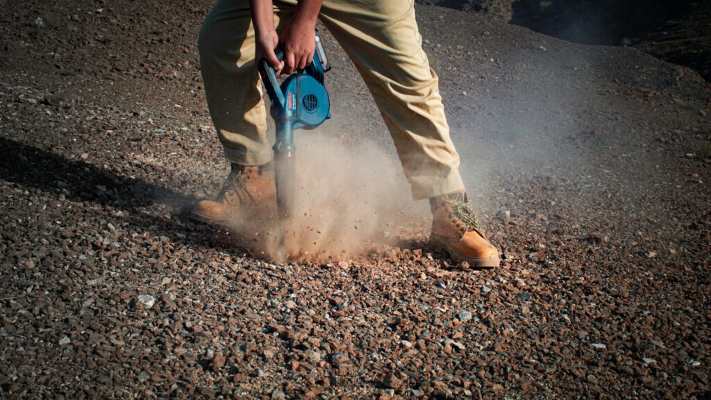 man blowing dust particles off the ground