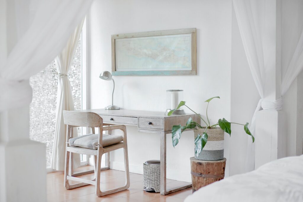 a white bedroom with a light wooden desk