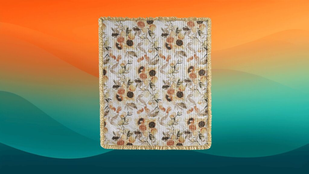 white quilt with sunflowers and leaves in front of an orange and teal background