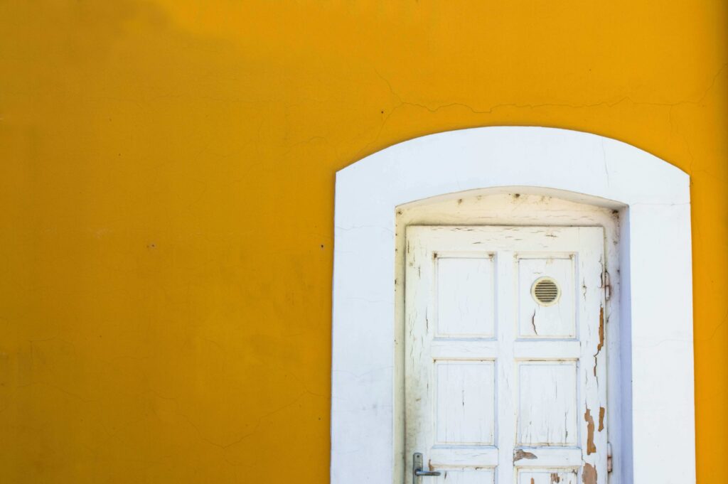 yellow wall and white door with cracked lead paint