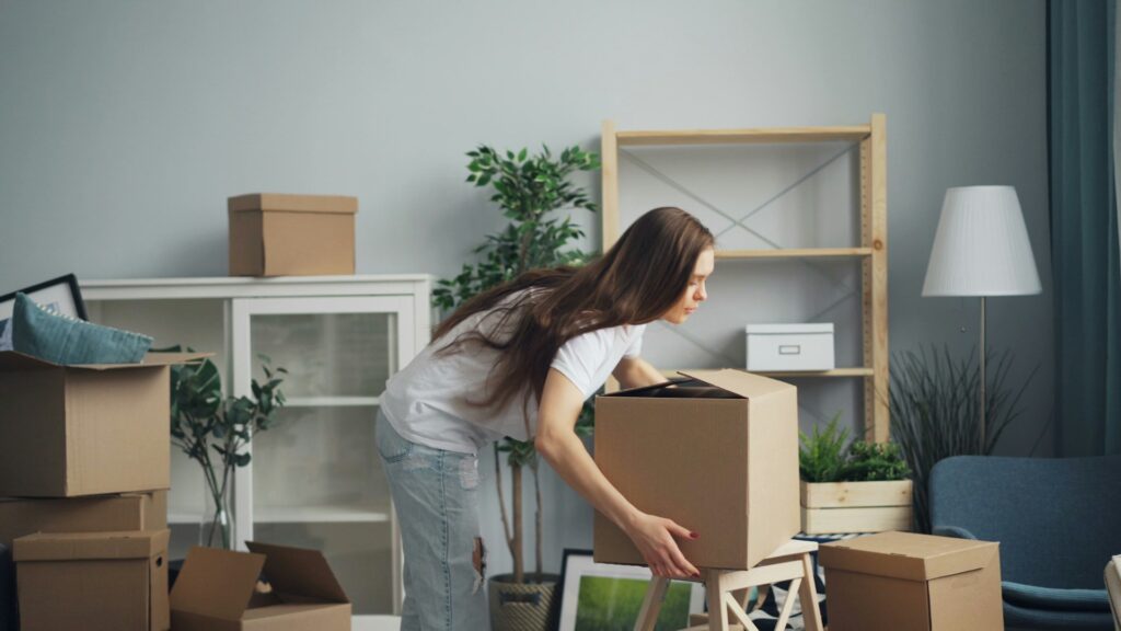 girl holding box and packing her house to move