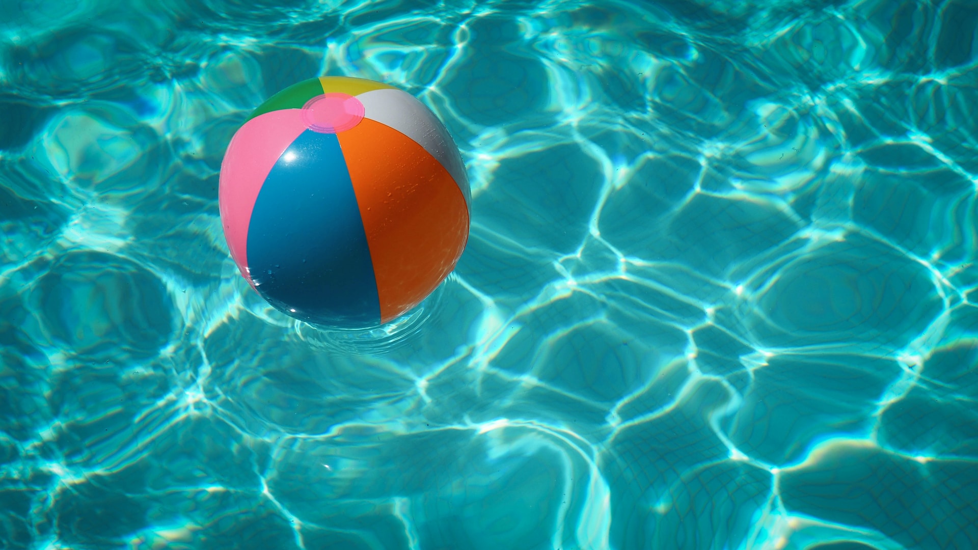 Beach ball floating in clear pool water.