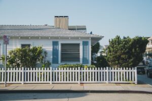 cheapest states to live in - house with picket fence and street in front.