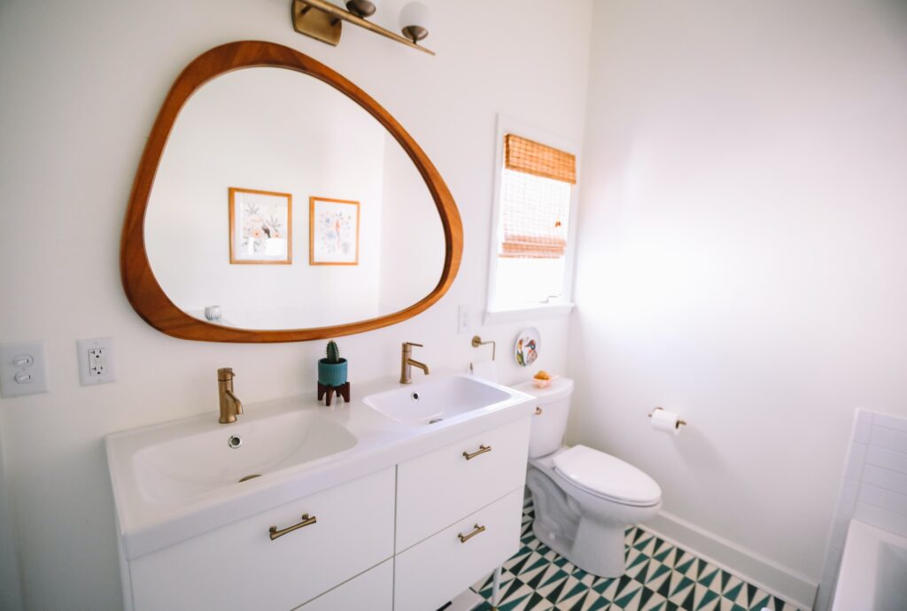 a large mirror hanging in an all white bathroom by someone who knows how to hang a heavy mirror