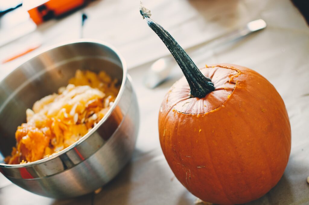 Pumpkin beside a bowl of seeds.